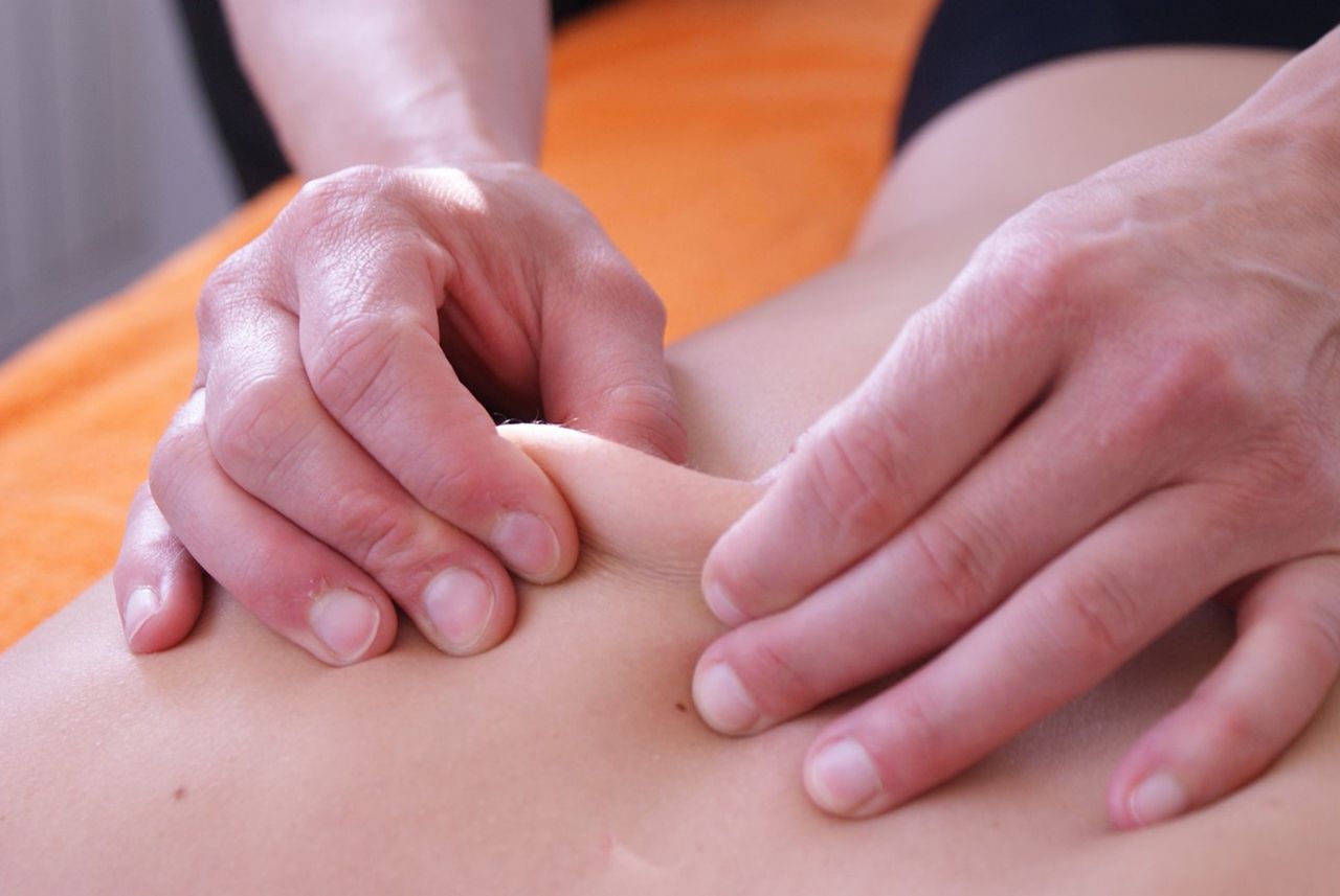 Hände massieren die Haut am Rücken einer Person